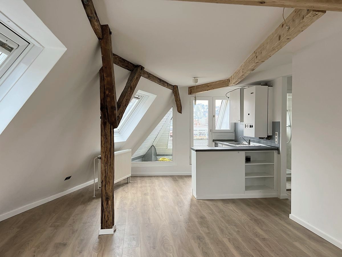 Wohnraum unter einem alten Dachstuhl mit sichtbarem Fachwerk und offener Küche