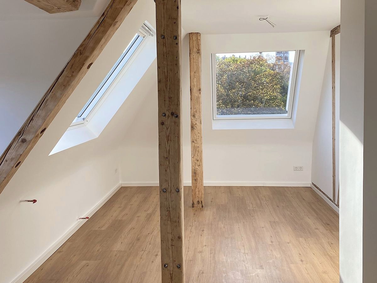 Ausgebautes Dachgeschoss mit freigelegten Holzbalken, Dachfenster und neuem Boden